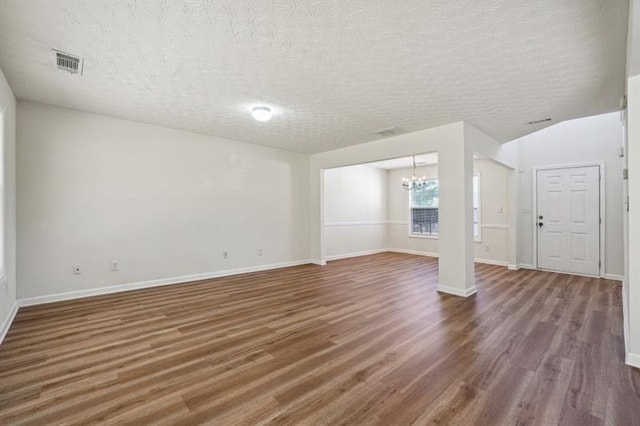 unfurnished living room with a chandelier, dark wood-type flooring, and a textured ceiling