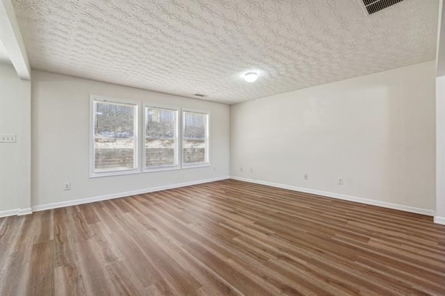 unfurnished room featuring hardwood / wood-style flooring and a textured ceiling