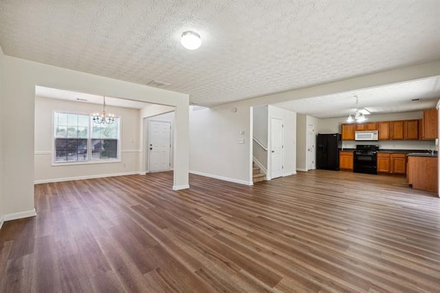 unfurnished living room with a textured ceiling, a chandelier, and dark hardwood / wood-style floors