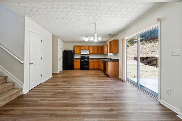 kitchen with a chandelier, a textured ceiling, decorative light fixtures, and black appliances