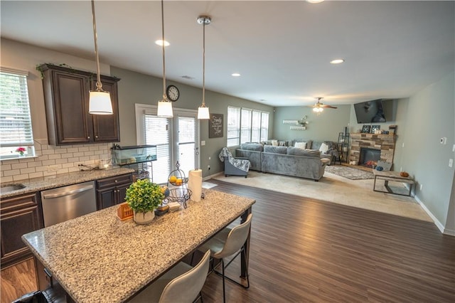 kitchen featuring stainless steel dishwasher, a center island, hanging light fixtures, a kitchen breakfast bar, and dark brown cabinetry