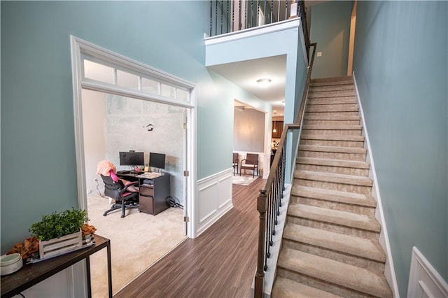 stairway with a high ceiling and hardwood / wood-style floors