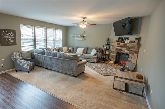 living room with ceiling fan, light wood-type flooring, and a stone fireplace