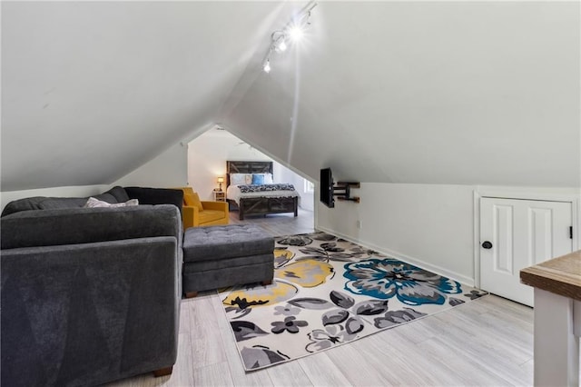 living room featuring vaulted ceiling, rail lighting, and light hardwood / wood-style flooring