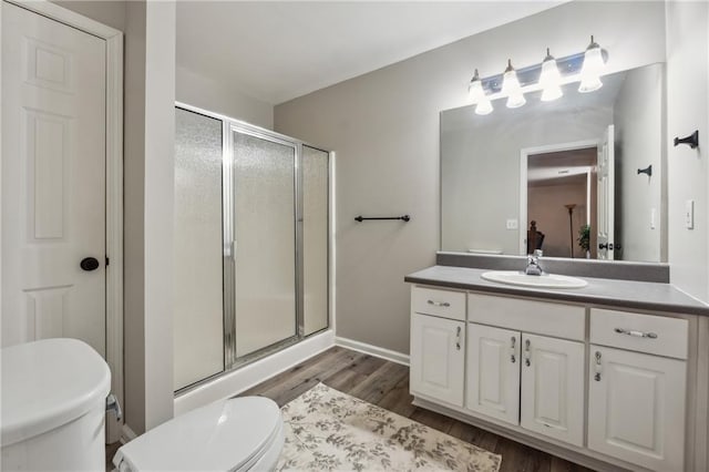 bathroom with walk in shower, vanity, toilet, and hardwood / wood-style floors