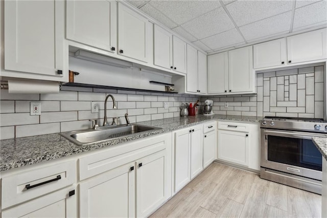 kitchen with sink, gas range, and white cabinets