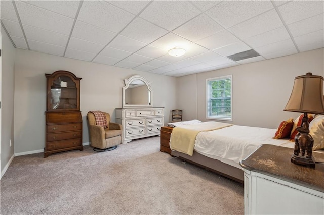 bedroom with a drop ceiling and light colored carpet