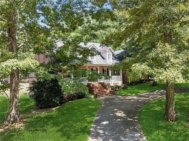 cape cod home with covered porch and a front lawn