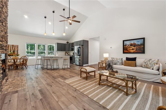 living room featuring high vaulted ceiling, light hardwood / wood-style floors, and ceiling fan