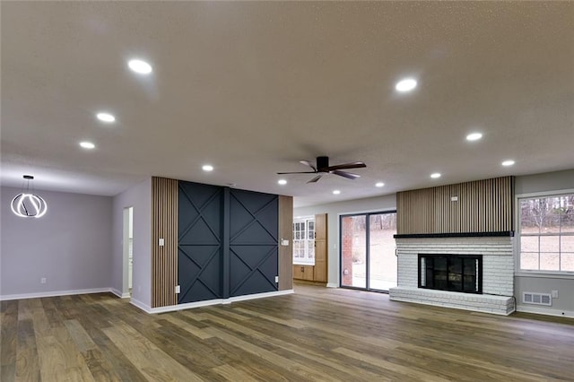 unfurnished living room featuring dark hardwood / wood-style flooring, a fireplace, and ceiling fan