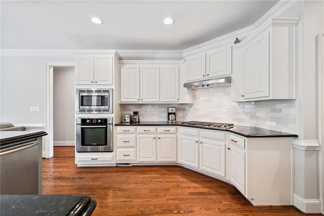 kitchen with under cabinet range hood, dark wood finished floors, appliances with stainless steel finishes, and white cabinetry