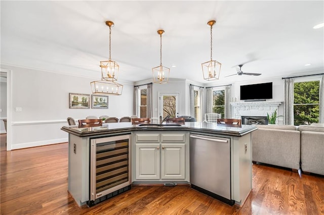 kitchen featuring beverage cooler, a sink, dark countertops, open floor plan, and dishwasher