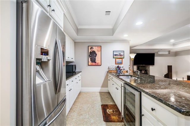 kitchen featuring a tray ceiling, ornamental molding, wine cooler, white cabinets, and stainless steel fridge