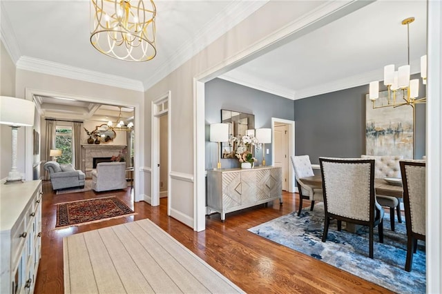 dining room featuring wood finished floors, coffered ceiling, a chandelier, and a fireplace