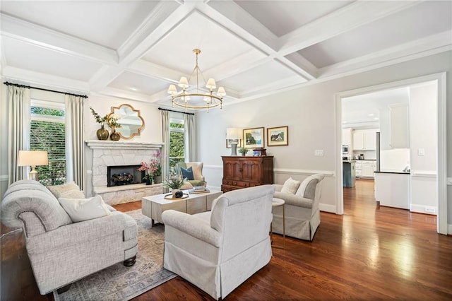 living area featuring coffered ceiling, beam ceiling, a stone fireplace, dark wood-type flooring, and a notable chandelier