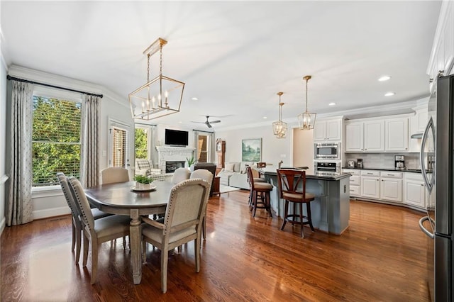 dining space with dark wood finished floors, a fireplace, and crown molding