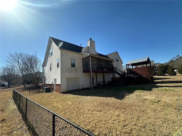 rear view of house featuring cooling unit, a garage, a yard, and a sunroom