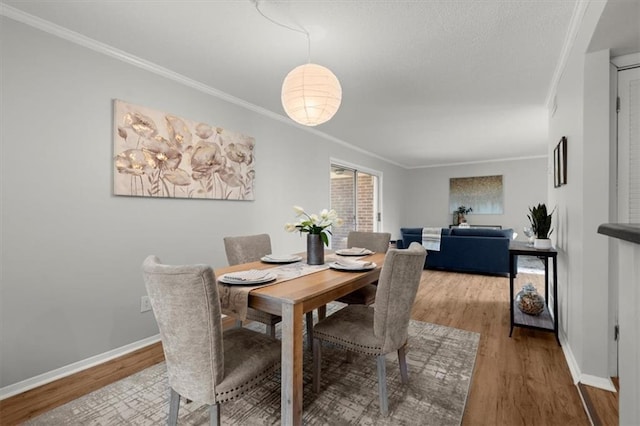 dining space with crown molding and light hardwood / wood-style flooring