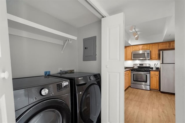 clothes washing area with electric panel, independent washer and dryer, and light hardwood / wood-style flooring
