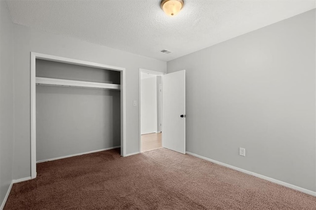 unfurnished bedroom with a closet, a textured ceiling, and dark colored carpet