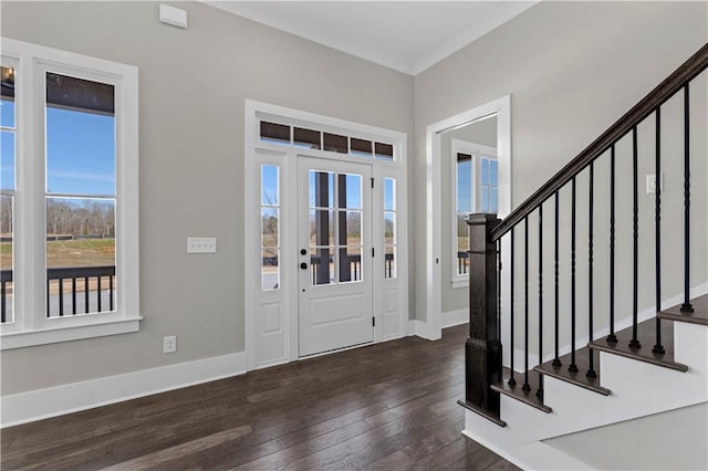 entrance foyer featuring dark wood-type flooring, ornamental molding, baseboards, and stairs