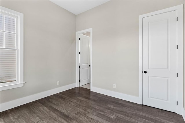 unfurnished bedroom featuring baseboards and dark wood-style flooring