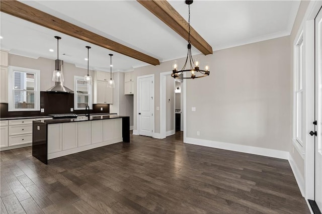 kitchen featuring dark countertops, wall chimney exhaust hood, baseboards, and dark wood-style flooring