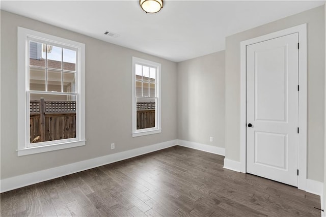 spare room with baseboards, dark wood finished floors, and a wealth of natural light