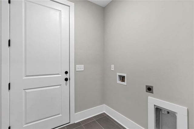 clothes washing area with hookup for a washing machine, electric dryer hookup, dark tile patterned flooring, laundry area, and baseboards