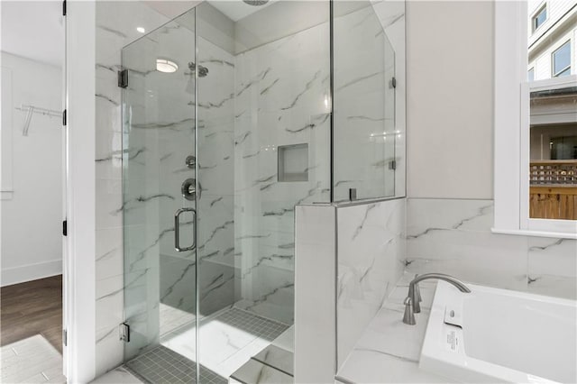 bathroom featuring a garden tub, wood finished floors, and a shower stall