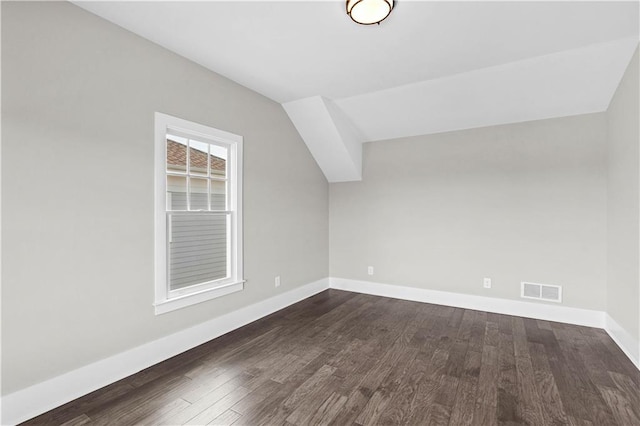 additional living space with lofted ceiling, dark wood finished floors, visible vents, and baseboards