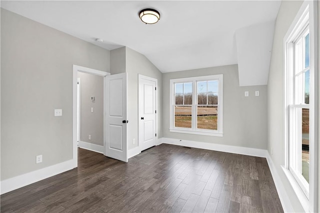 unfurnished room featuring lofted ceiling, baseboards, and dark wood-type flooring