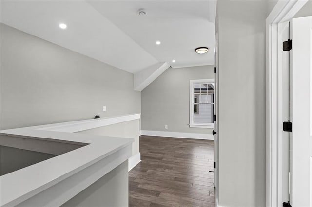 corridor with dark wood-style floors, baseboards, vaulted ceiling, and recessed lighting