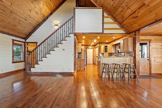 interior space featuring a breakfast bar, wood-type flooring, wooden walls, and wood ceiling