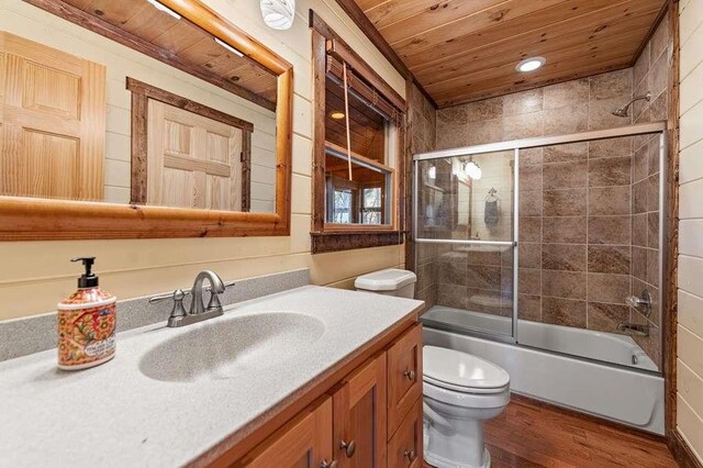 full bathroom featuring vanity, shower / bath combination with glass door, wooden ceiling, hardwood / wood-style flooring, and toilet