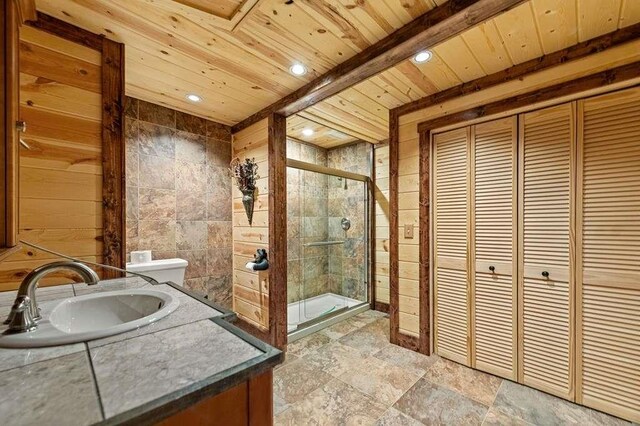 bathroom with beamed ceiling, vanity, a shower with shower door, and tile walls