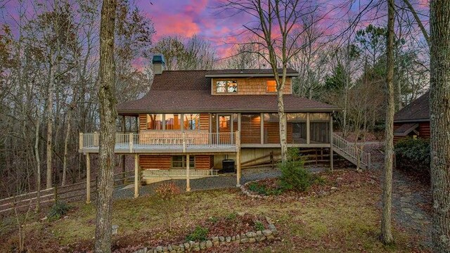 back house at dusk featuring a wooden deck and central AC unit