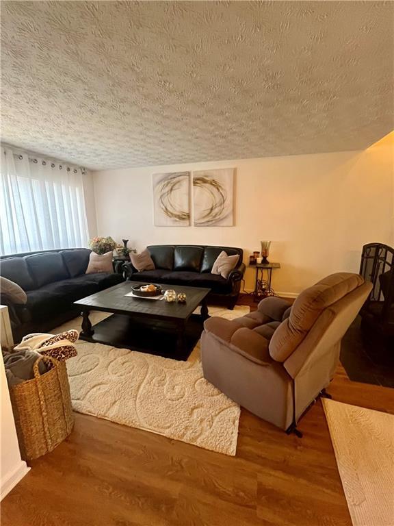 living area featuring a textured ceiling and wood finished floors