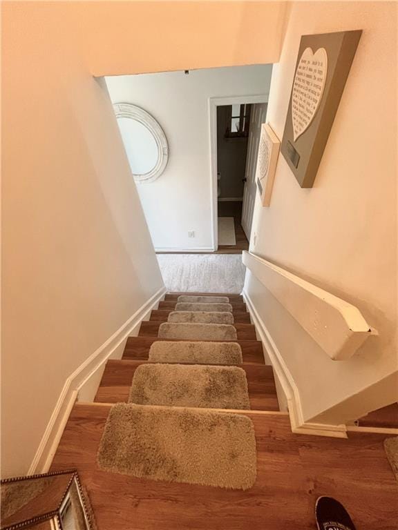 staircase with baseboards and wood finished floors