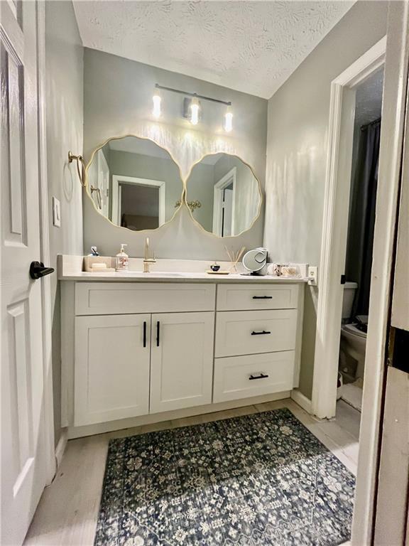 bathroom featuring vanity, toilet, and a textured ceiling