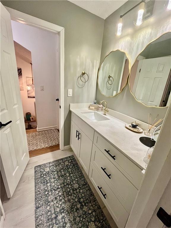 bathroom featuring double vanity, baseboards, and a sink