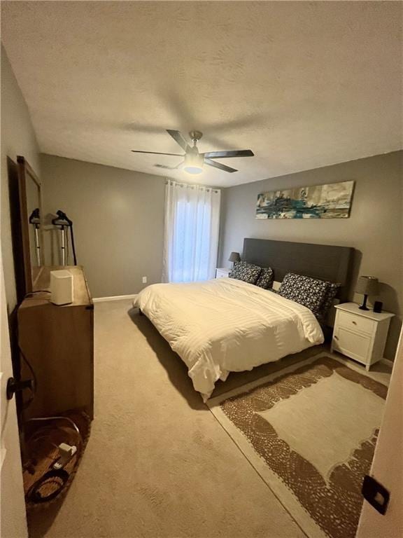 bedroom with baseboards, carpet flooring, a textured ceiling, and a ceiling fan