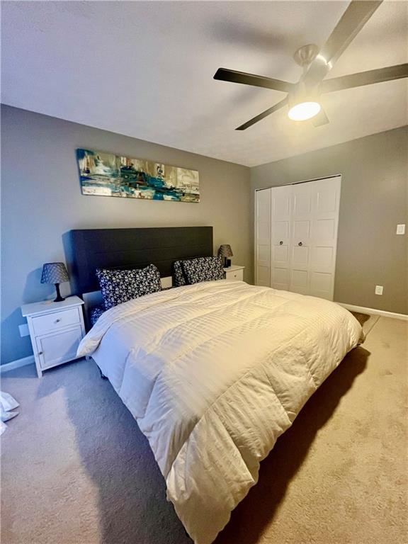 bedroom featuring a closet, baseboards, carpet floors, and ceiling fan