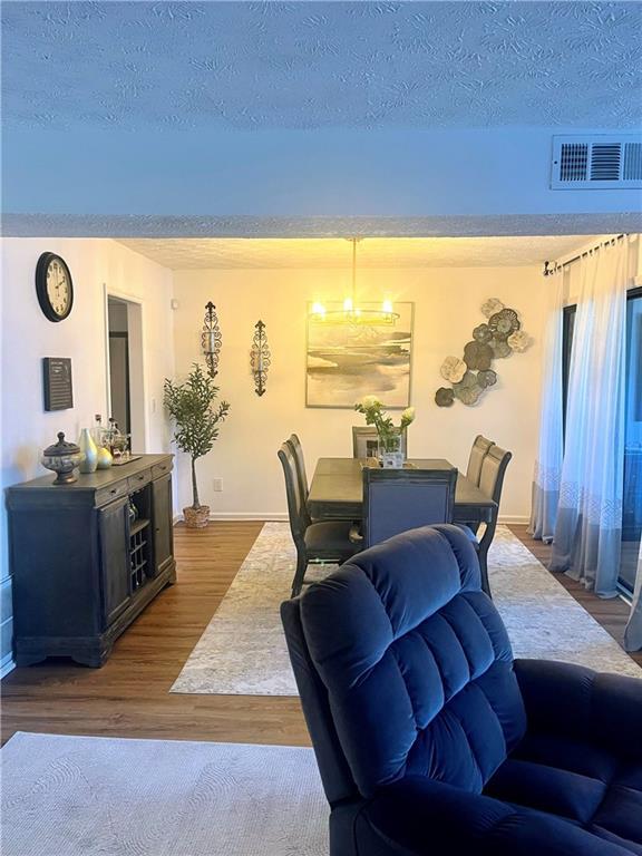 dining area with visible vents, dark wood-style flooring, and a textured ceiling