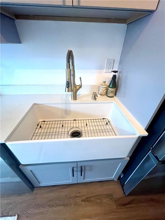 interior details featuring a sink, dark wood finished floors, and light countertops