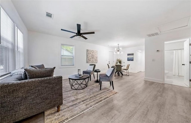 living room featuring light wood-type flooring and ceiling fan with notable chandelier