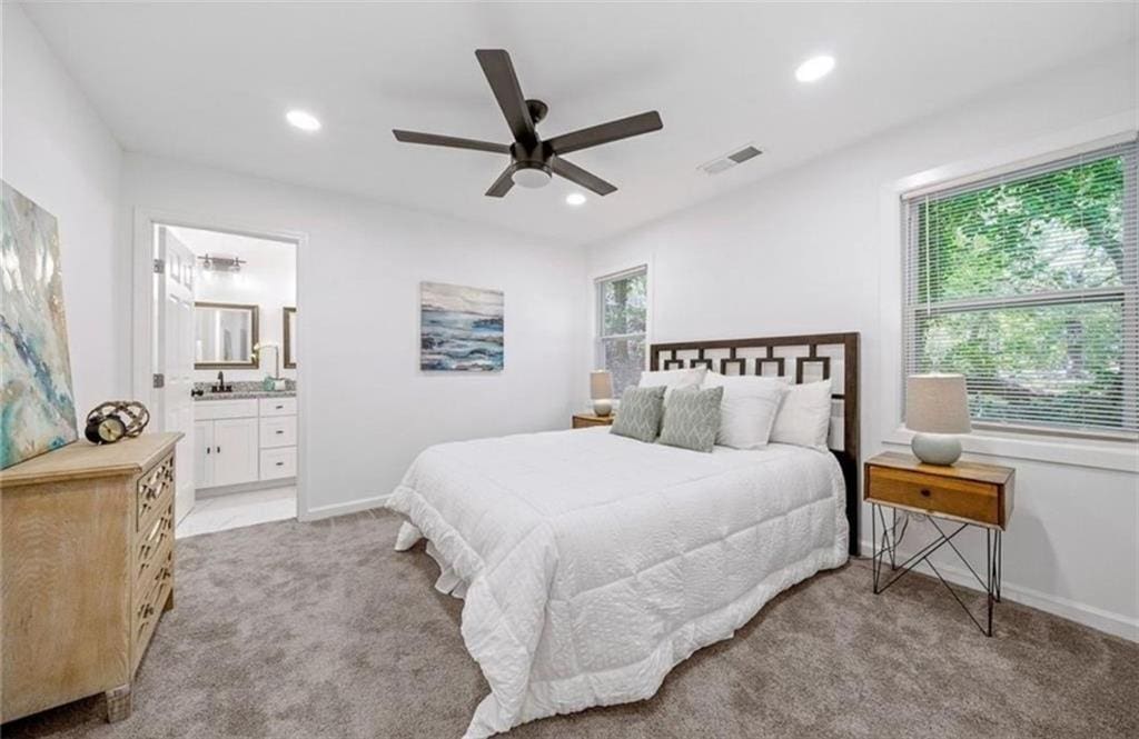 carpeted bedroom featuring ensuite bath, sink, and ceiling fan