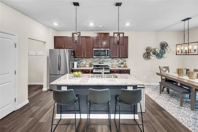 104 Auburn Crossing Way, Auburn, GA 30011 - kitchen featuring appliances with stainless steel finishes, dark wood-type flooring, decorative backsplash, baseboards, and a kitchen island with sink