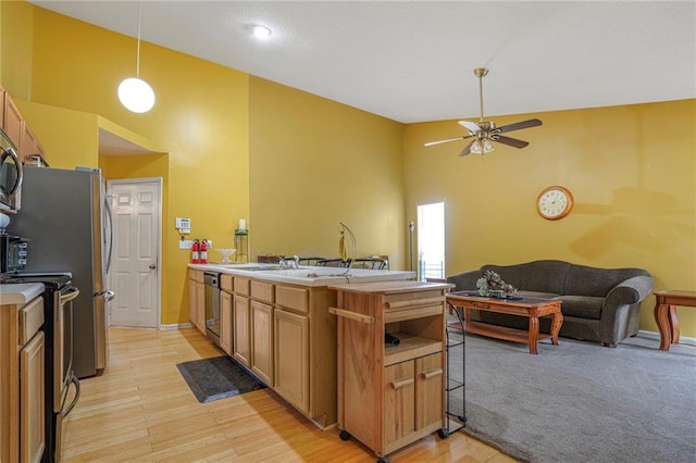 kitchen featuring decorative light fixtures, light countertops, appliances with stainless steel finishes, open floor plan, and a peninsula