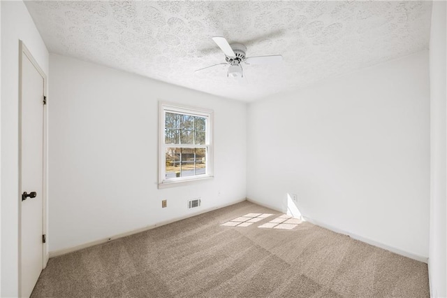 carpeted spare room featuring a ceiling fan, visible vents, and a textured ceiling